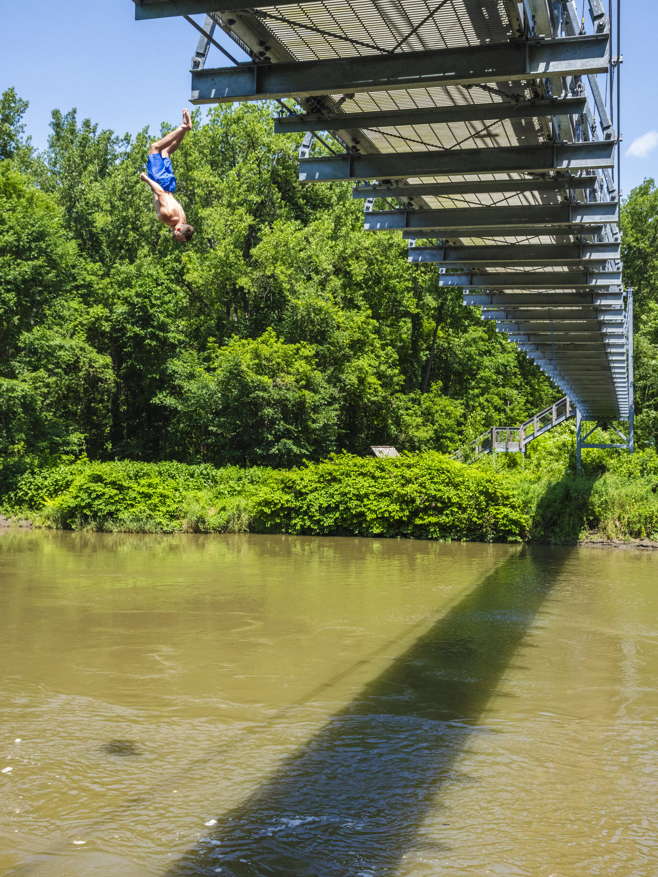 Diving off a tall railroad bridge into a river below